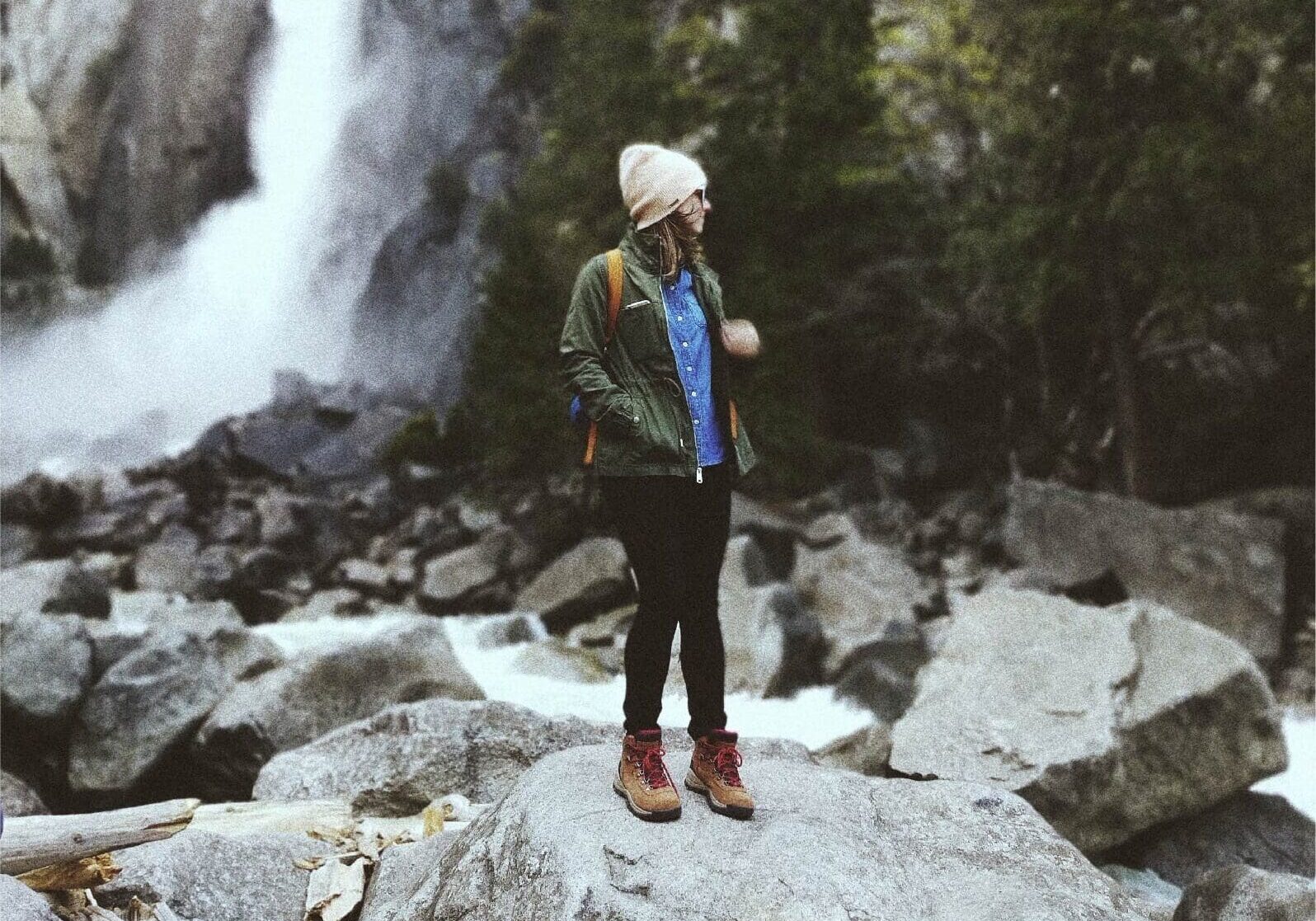 A person standing on top of rocks near a waterfall.